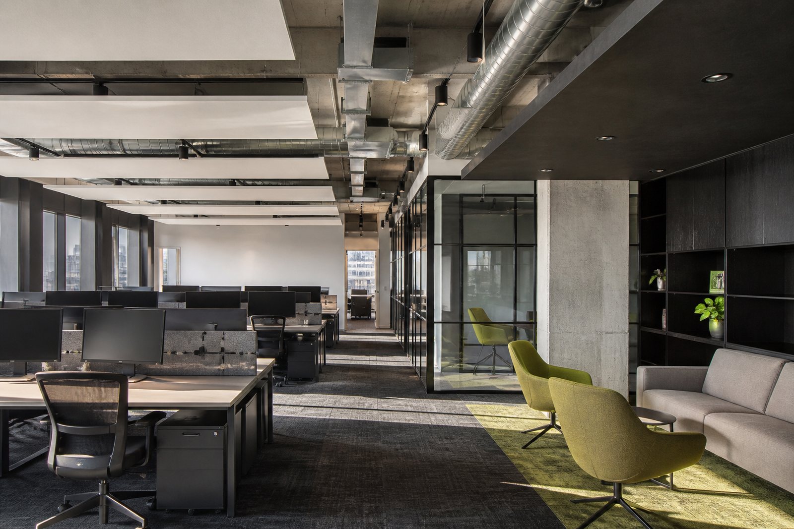 A completed open-plan office with exposed services and lime-accented furniture